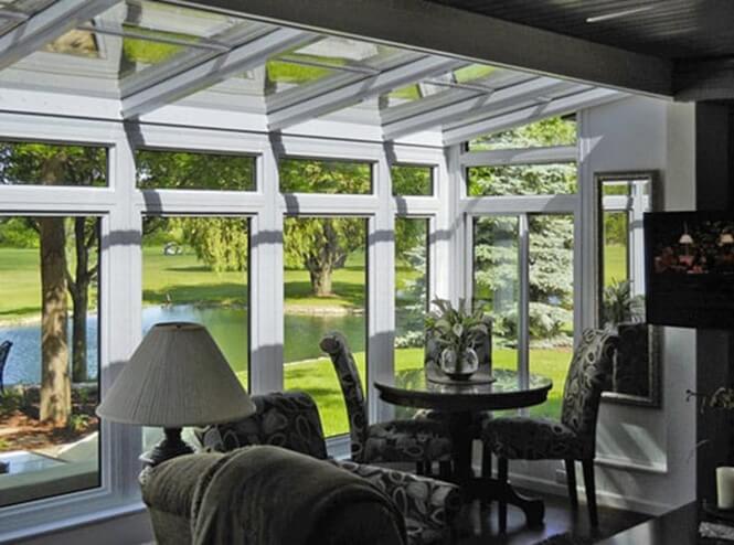 A hybrid sunroom that overlooks a backyard and pond.